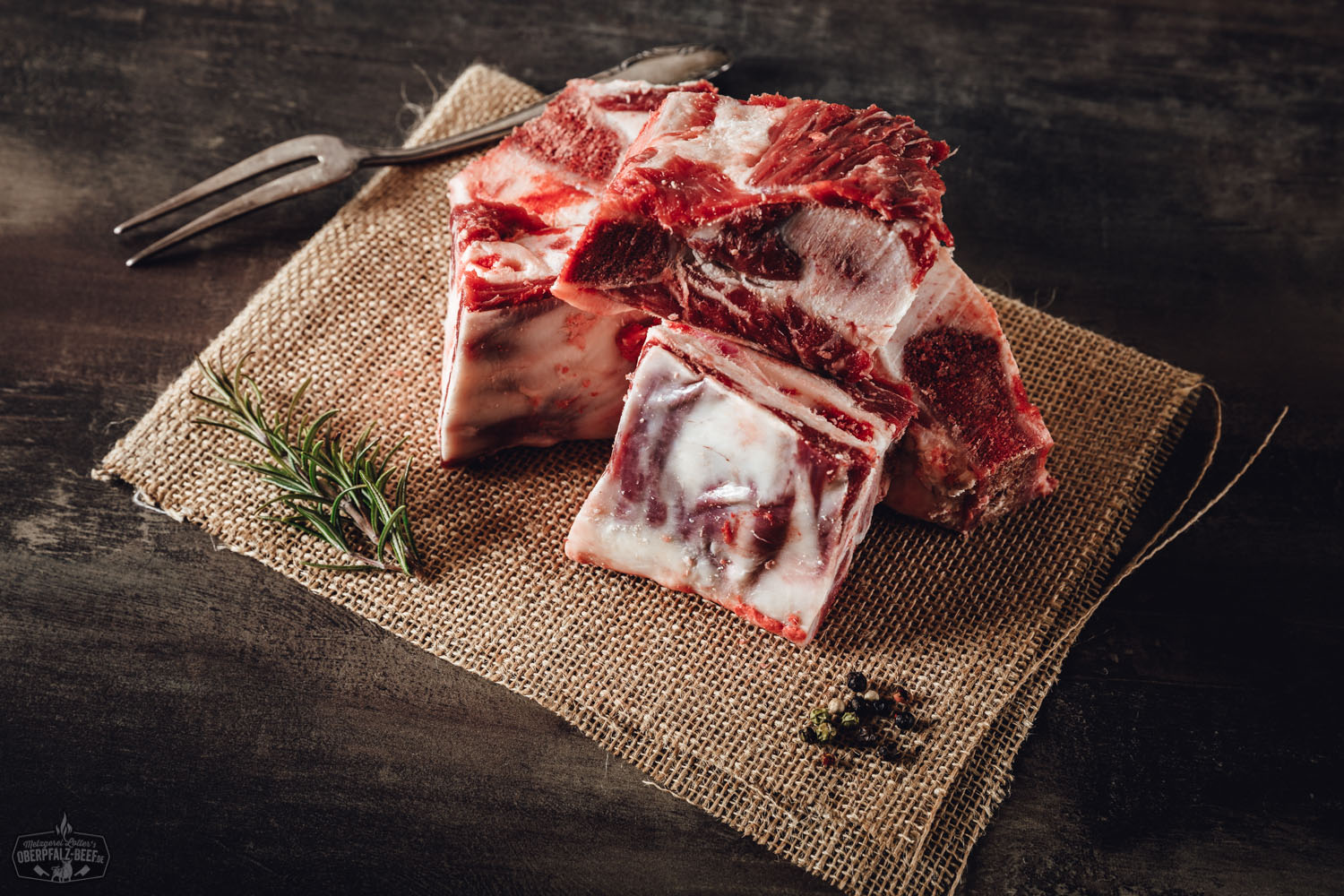 Rohes Brustbein vom Oberpfalz-Rind auf dunkler Steinfläche, kräftig marmoriertes Rindfleisch mit sichtbarem Knochen, fotografiert in hoher Auflösung für Fleischliebhaber und BBQ-Enthusiasten.