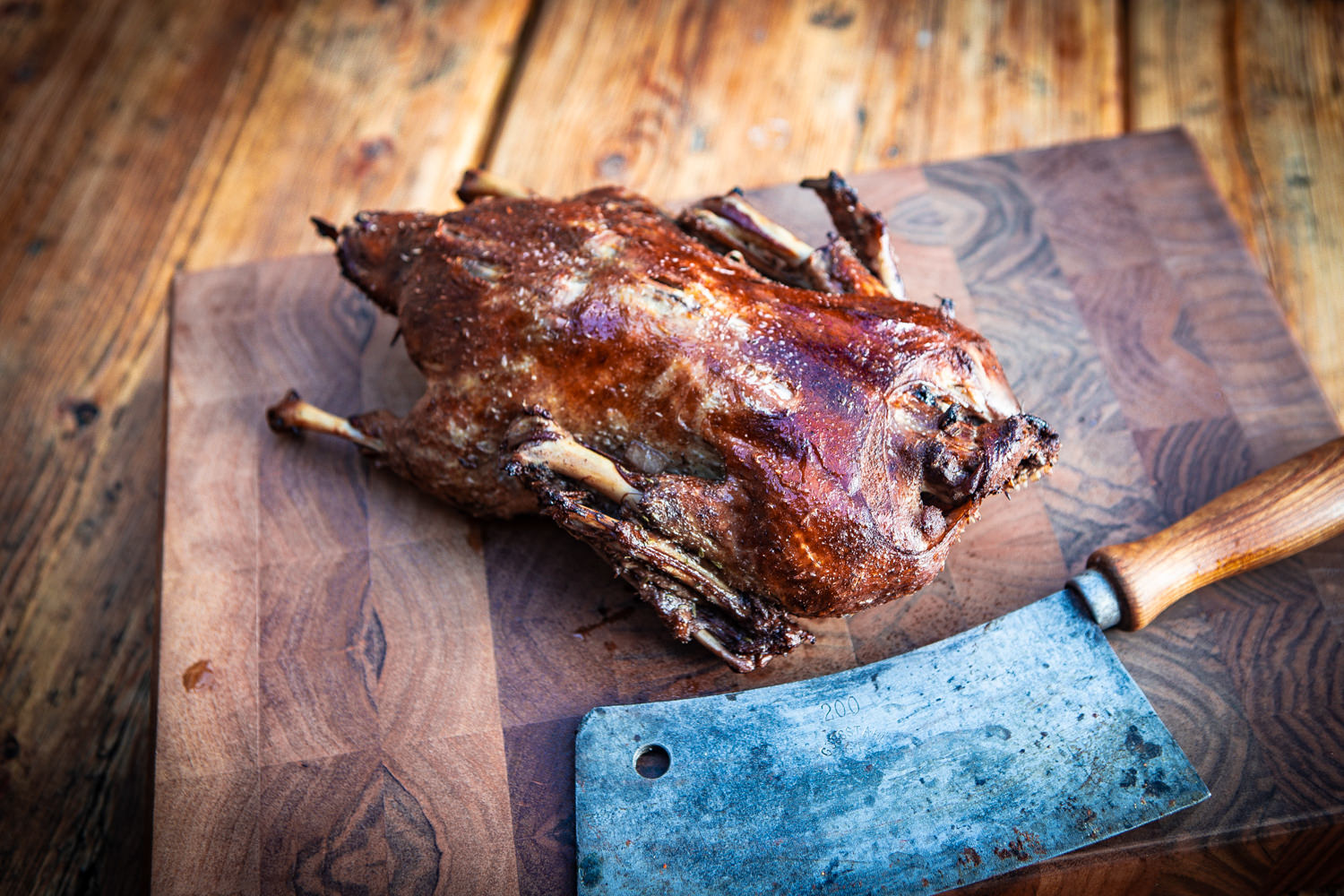 Bild zeigt eine große, frisch zubereitete Oberpfälzer Bauernente auf einem rustikalen Holztisch, umgeben von Kräutern und Gemüse. Die knusprige Haut ist goldbraun gebraten, ideal für Feinschmecker und Liebhaber bayerischer Spezialitäten.