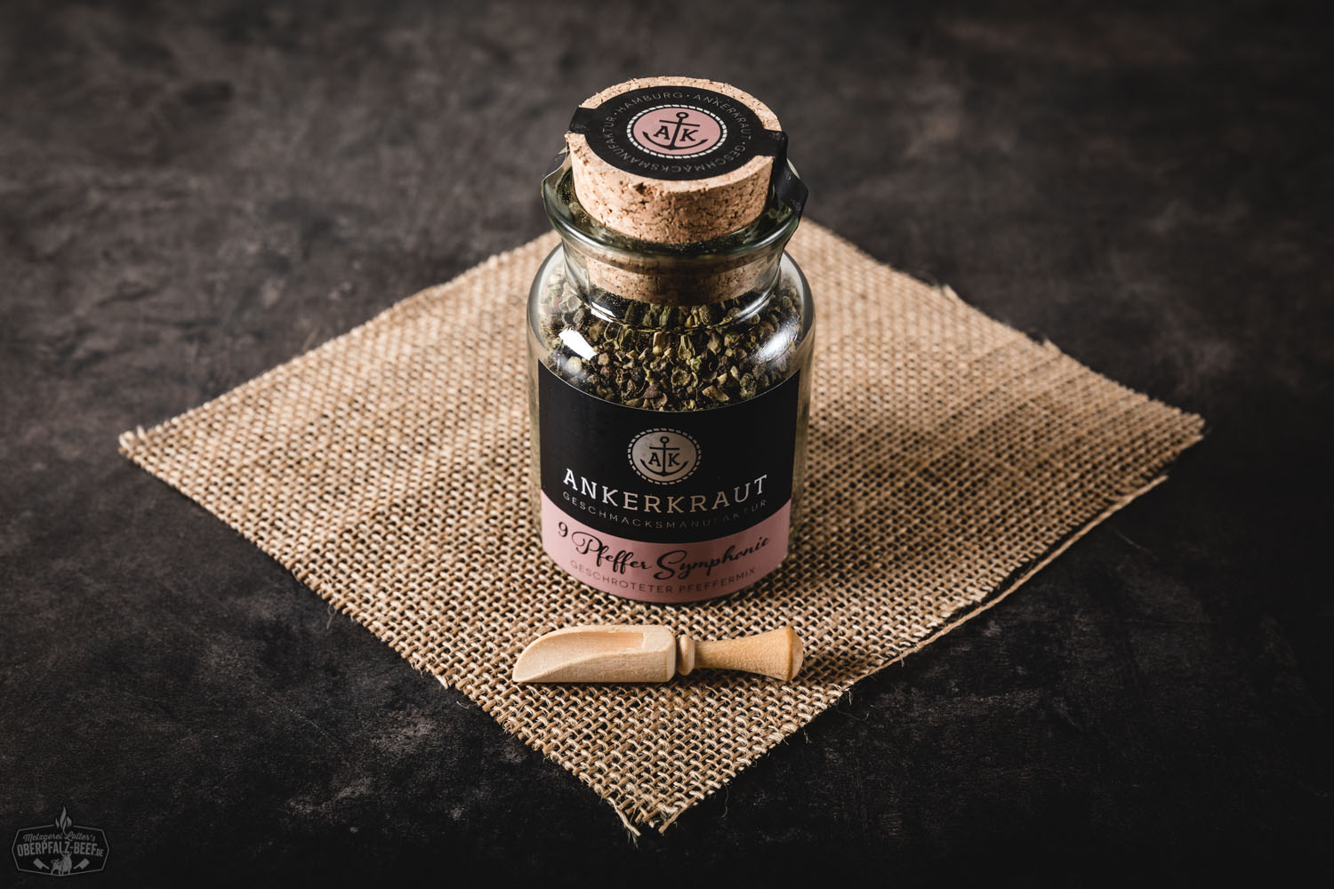 Gewürzglas "Pfeffer Symphonie" von Ankerkraut auf hellem Untergrund, mit grob gemahlenem, buntem Pfeffer in Rot, Schwarz, Weiß und Grün daneben; hochwertige Gewürzmischung für Fleischgerichte und Grillgerichte, ideal für BBQ und Steak-Liebhaber.
