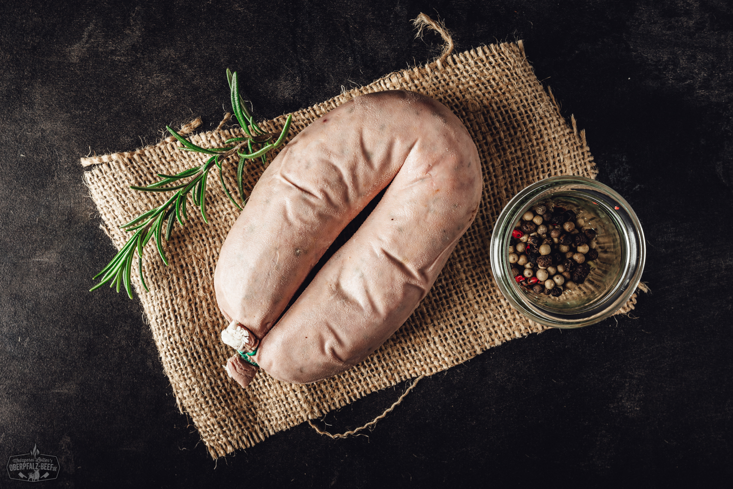 Frische Krautwurst vom Metzger – Hausgemachte Spezialität aus Bayern Cheese-Leberkäse goldbraun gebacken, aufgeschnitten auf einem Holzbrett angerichtet, mit sichtbar geschmolzenem Käse im Inneren; daneben Gewürze und frische Kräuter – herzhafte bayrische Spezialität zum Aufbacken.