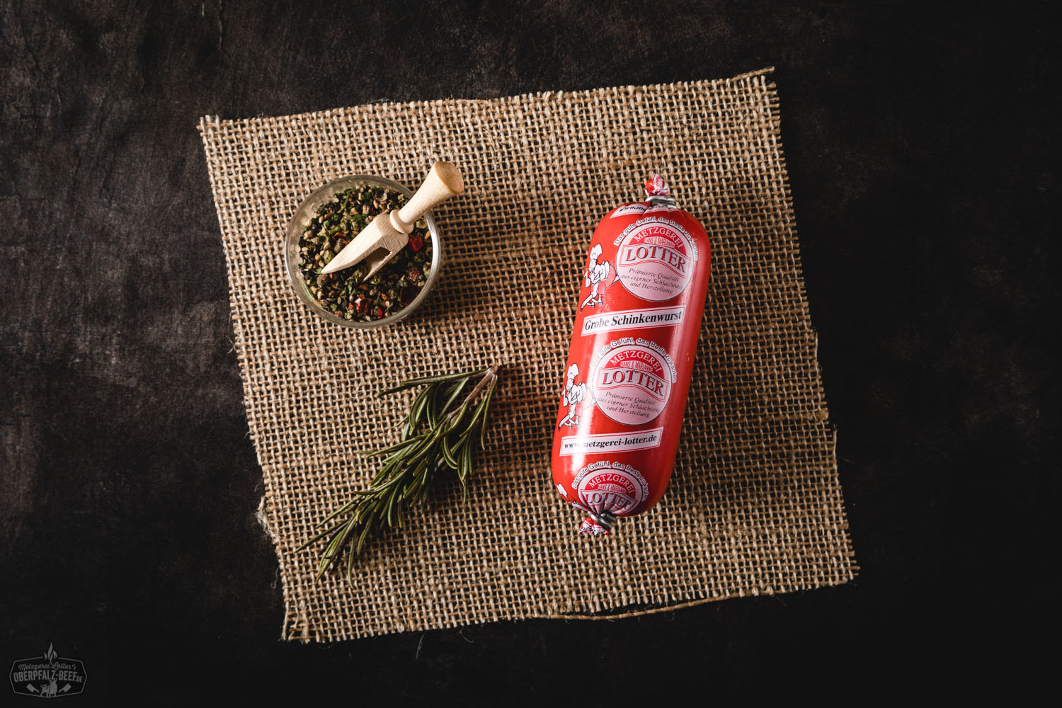 Grobe Schinkenwurst Mini in Scheiben auf einem Holzbrett angerichtet, daneben frische Petersilie und grobes Salz – traditionelle deutsche Wurstspezialität in rustikaler Präsentation.