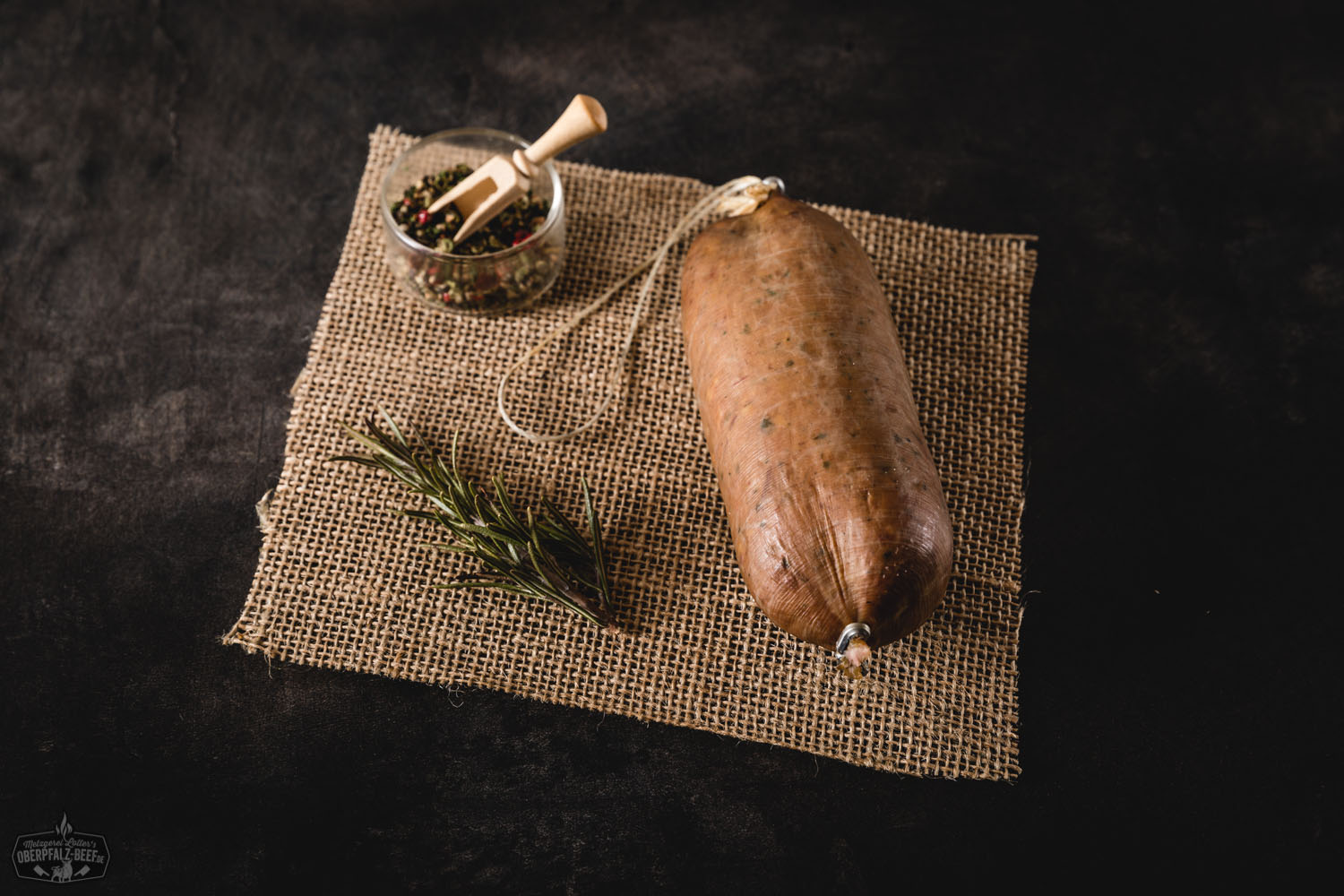 Original Oberpfälzer Bauernleberwurst schwarzgeräuchert – traditionelle Hausmacher-Wurst aus Bayern Schwarzgeräucherte Oberpfälzer Bauernleberwurst als aufgeschnittene Wurstscheiben und im Naturdarm, angerichtet auf einem Holzbrett mit frischem Brot, Zwiebelringen, Gurke und Petersilie – traditionelle bayerische Spezialität rustikal in Szene gesetzt.